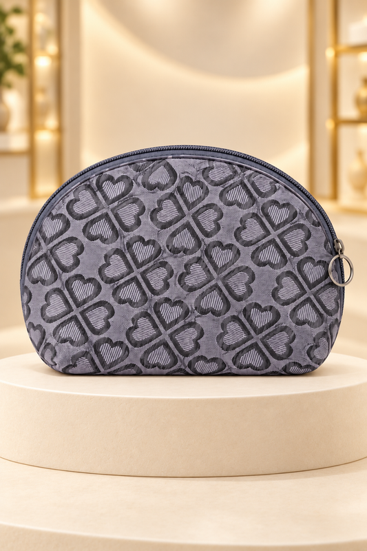 Gray heart-pattern makeup bag on a cream boutique display riser, shown unpackaged