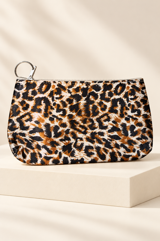Orange/Black leopard-print makeup bag shown unpackaged on a cream boutique display riser
