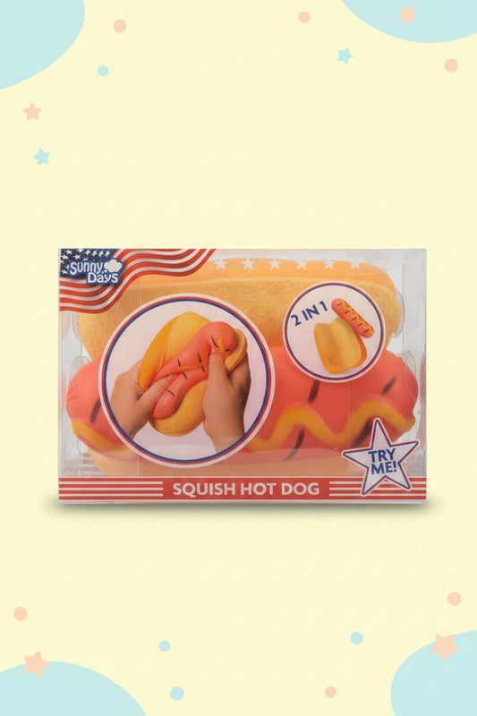 Sunny Days Squish Hot Dog toy in its original retail packaging, featuring a squishy hot dog in a bun with a pink sausage and yellow wavy lines, shown with a 'Try Me!' star badge and instructional graphics.