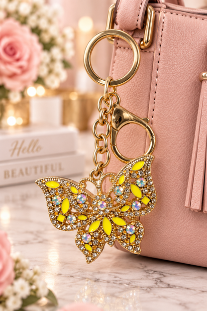 Gold-tone yellow rhinestone butterfly keychain on blush handbag
