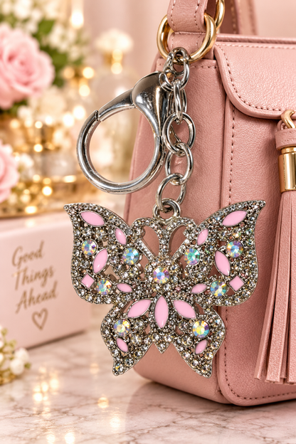 Silver-tone pink rhinestone butterfly keychain on blush handbag