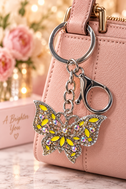 Silver-tone yellow rhinestone butterfly keychain on blush handbag