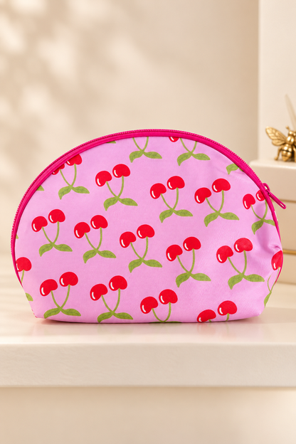 bright pink background, red paired cherries with light green stems/leaves; hot pink zipper and piping cherry-print makeup bag. One selected bag per purchase.
