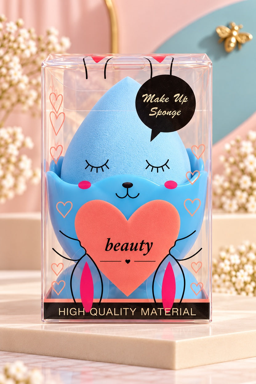 One individually boxed blue egg-shaped makeup sponge and coordinating stand; face graphics are printed on the clear box only