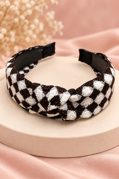 Close-up of brown and white checkered headband texture, top knot and black covered end tips