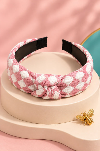 Pink checkered top-knot headband with white checks on a boutique display
