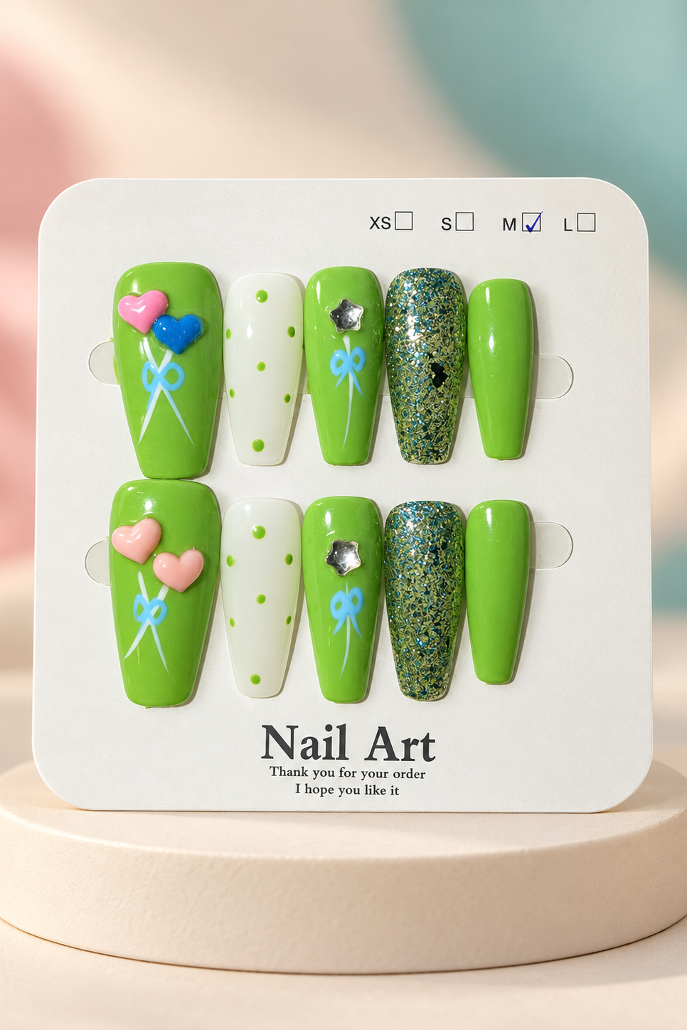 Original manufacturer card and lime green heart and bow nail set displayed without wrapper on cream plinth
