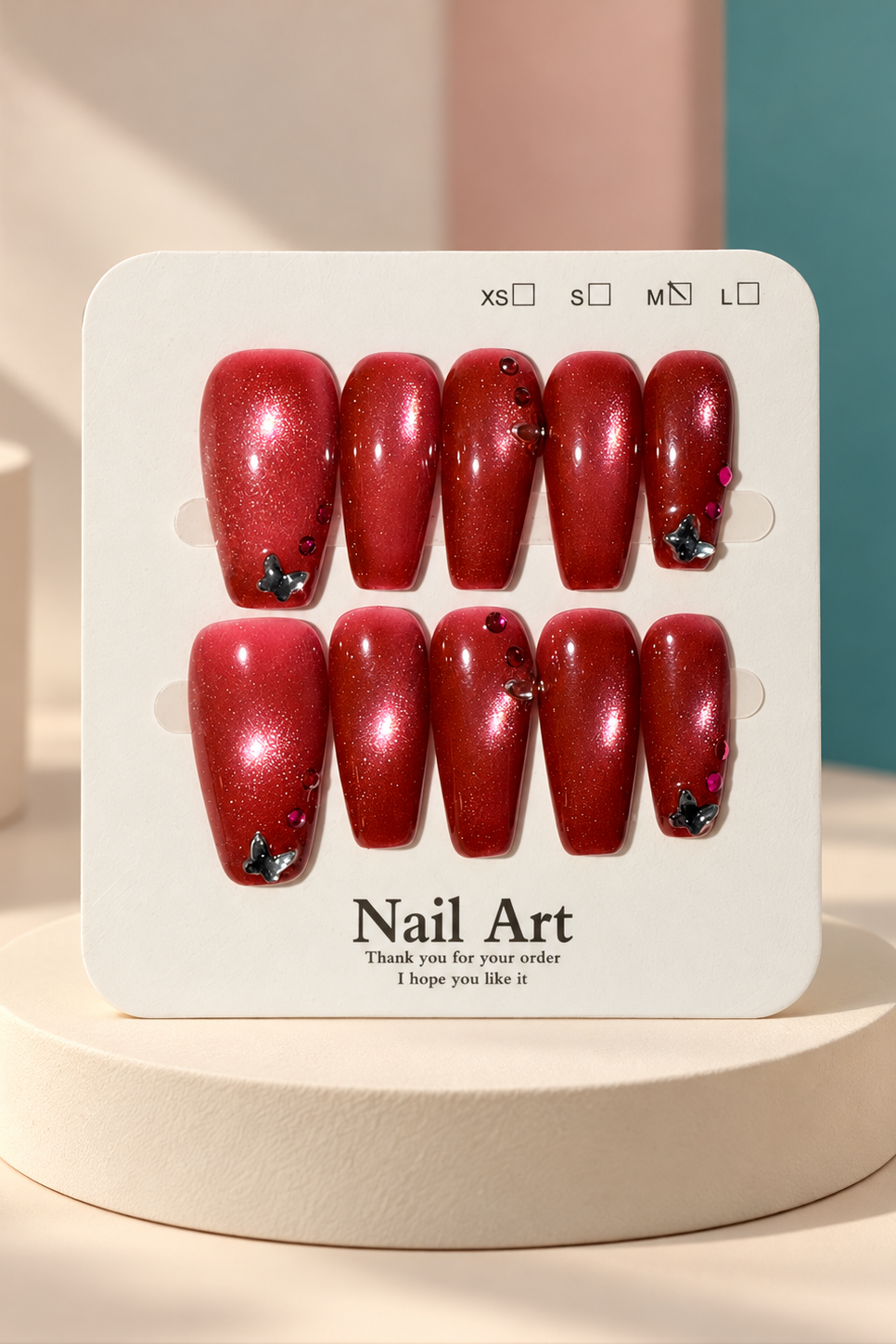 Original manufacturer card displaying red shimmer butterfly rhinestone coffin nails on cream plinth without wrapper