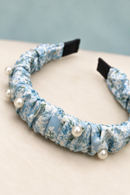 Close-up of blue floral gathered fabric, pearl-style beads and black covered end tips