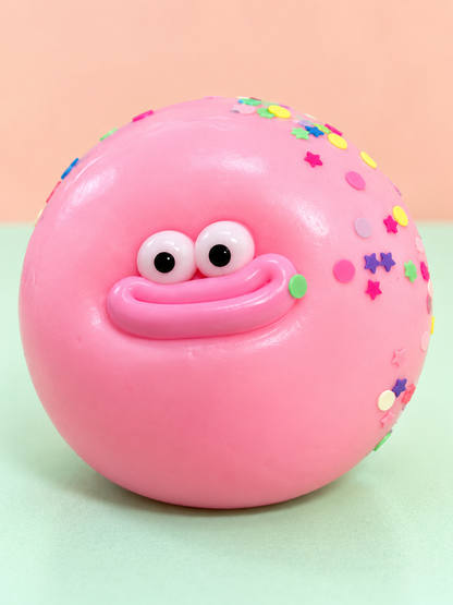 Pink Goofy Bun squishy ball with goofy face and colorful sprinkles