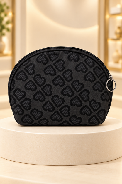 Black heart-pattern makeup bag on a cream boutique display riser, shown unpackaged
