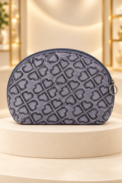 Gray heart-pattern makeup bag on a cream boutique display riser, shown unpackaged