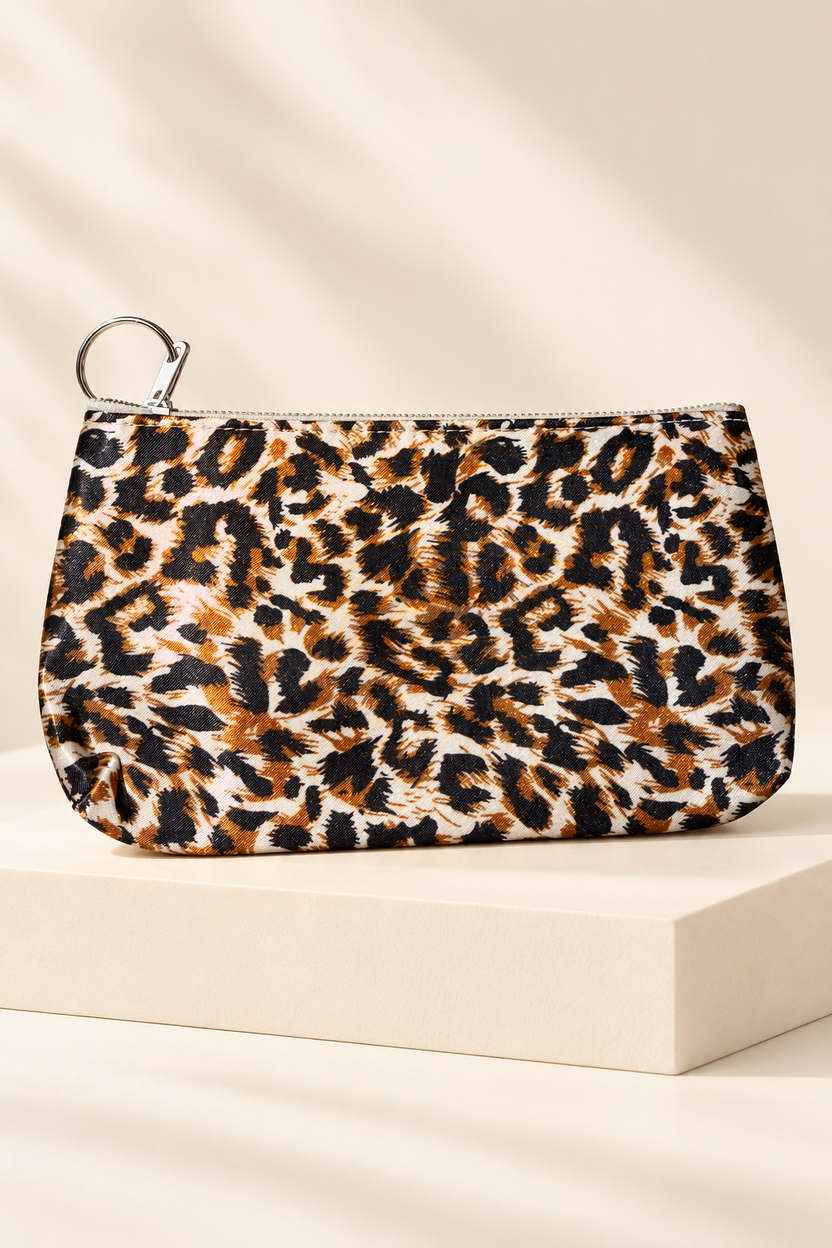Orange/Black leopard-print makeup bag shown unpackaged on a cream boutique display riser