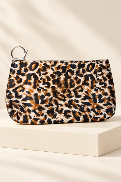 Orange/Black leopard-print makeup bag shown unpackaged on a cream boutique display riser