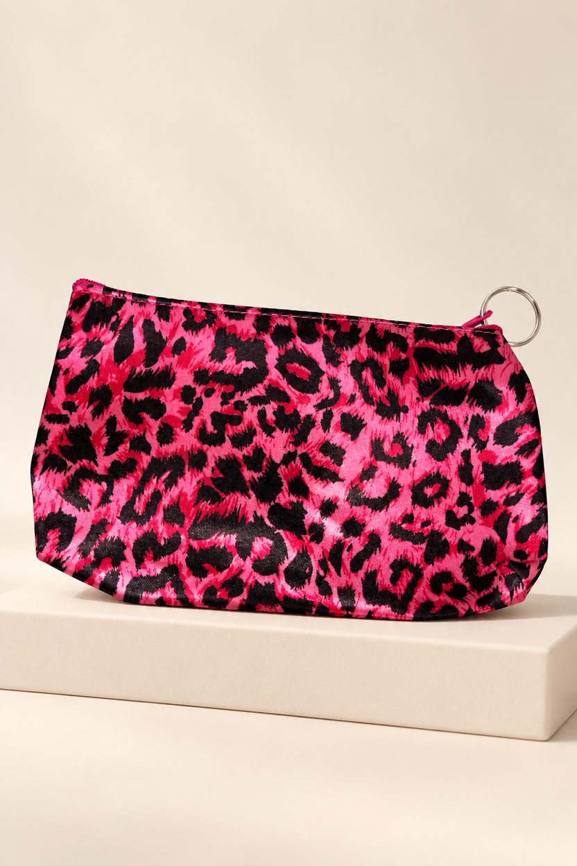 Hot Pink/Black leopard-print makeup bag shown unpackaged on a cream boutique display riser