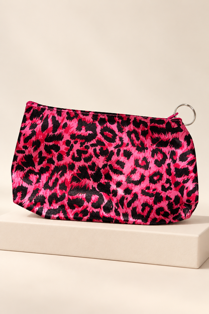 Hot Pink/Black leopard-print makeup bag shown unpackaged on a cream boutique display riser