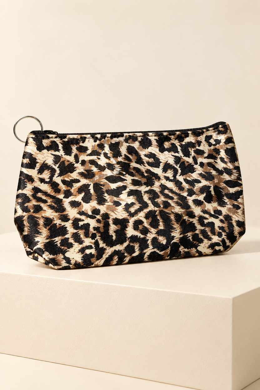 Tan/Black leopard-print makeup bag shown unpackaged on a cream boutique display riser