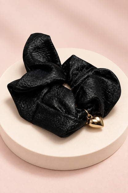 Black Melody heart-charm scrunchie with glossy gathered fabric and gold-tone heart