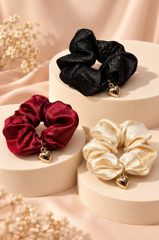 Melody heart-charm scrunchies in Burgundy, Black and Champagne; one selected hair tie sold