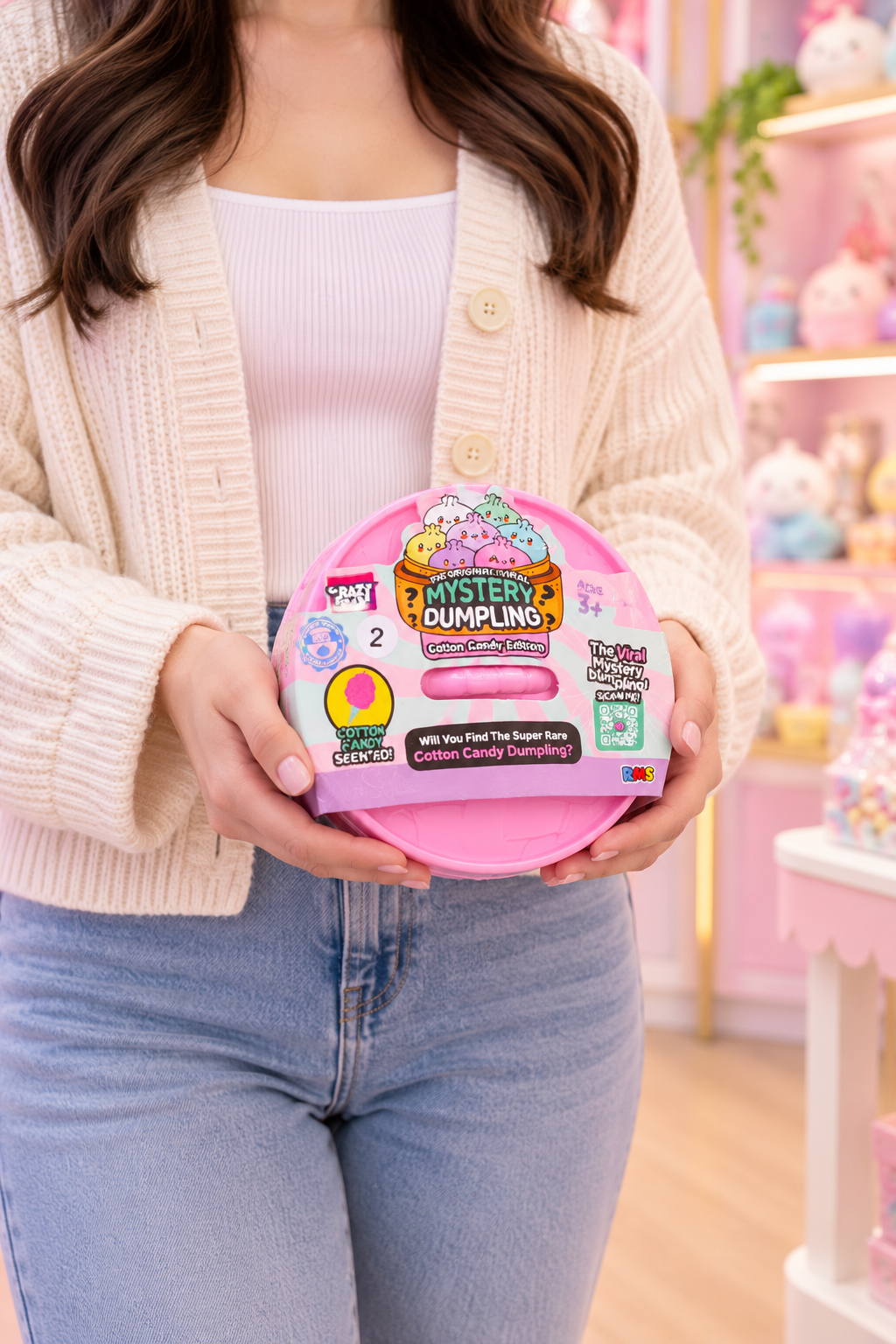 Adult holding sealed RMS Cotton Candy Edition mystery dumpling set in a pastel boutique setting.