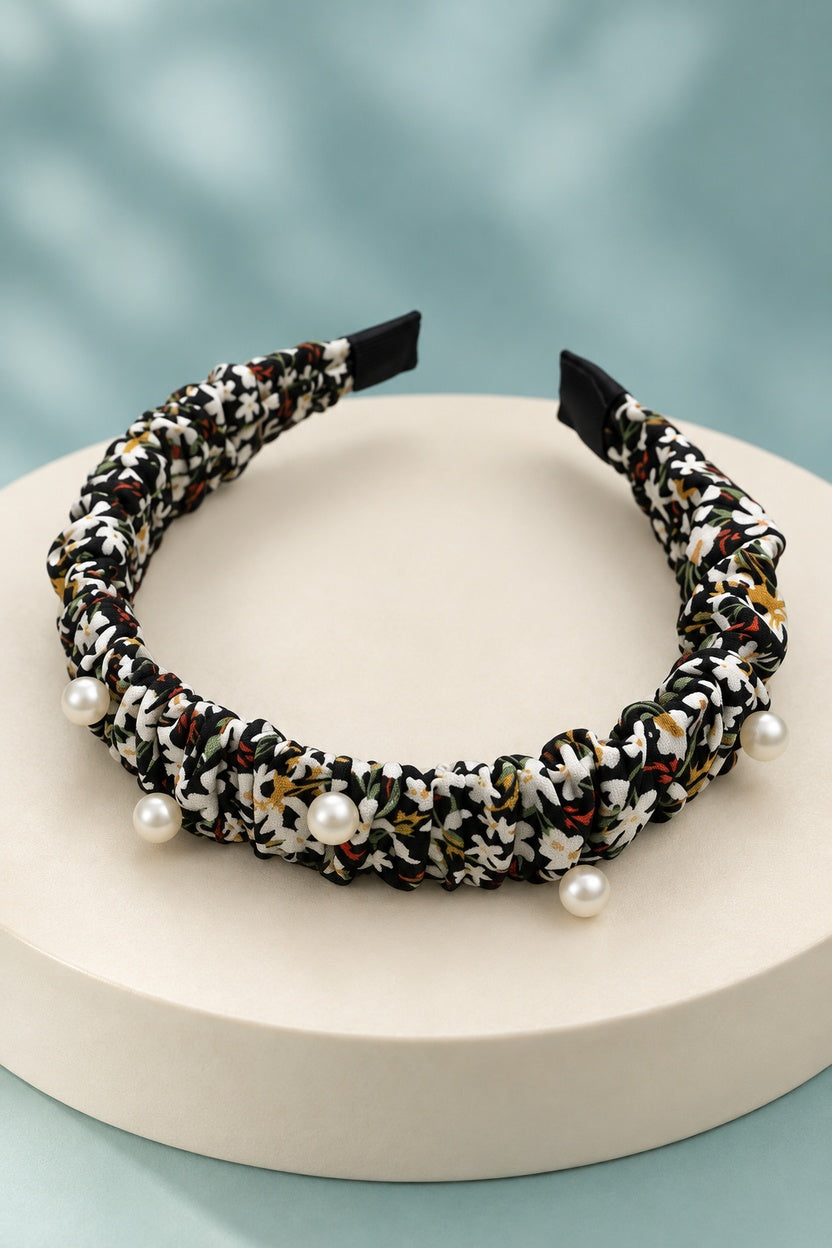 Black ruched floral headband with pearl-style beads on a boutique display