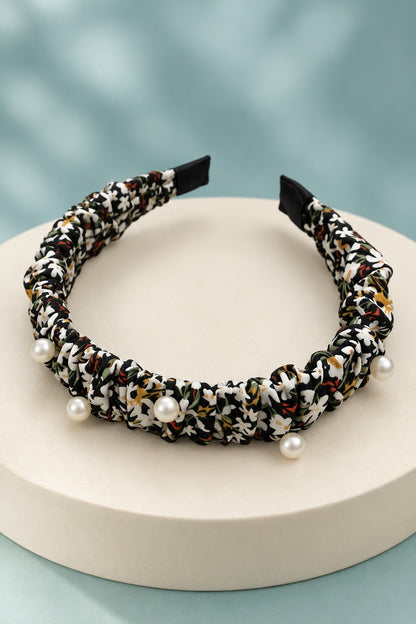 Black ruched floral headband with pearl-style beads on a boutique display