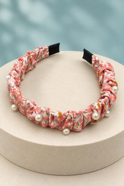 Pink ruched floral headband with pearl-style beads on a boutique display