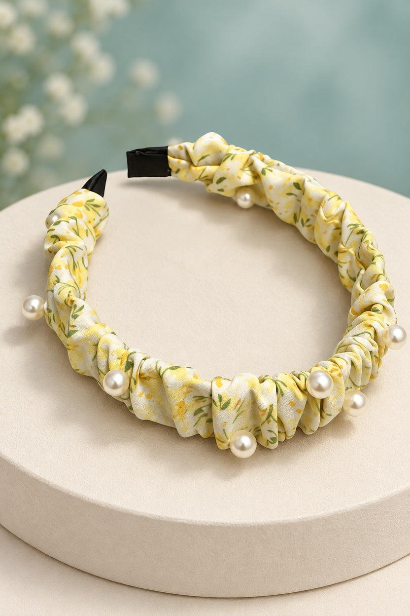 Yellow ruched floral headband with pearl-style beads on a boutique display