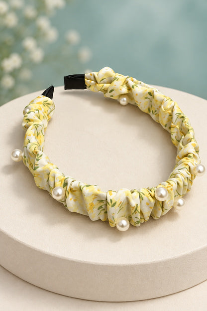 Yellow ruched floral headband with pearl-style beads on a boutique display