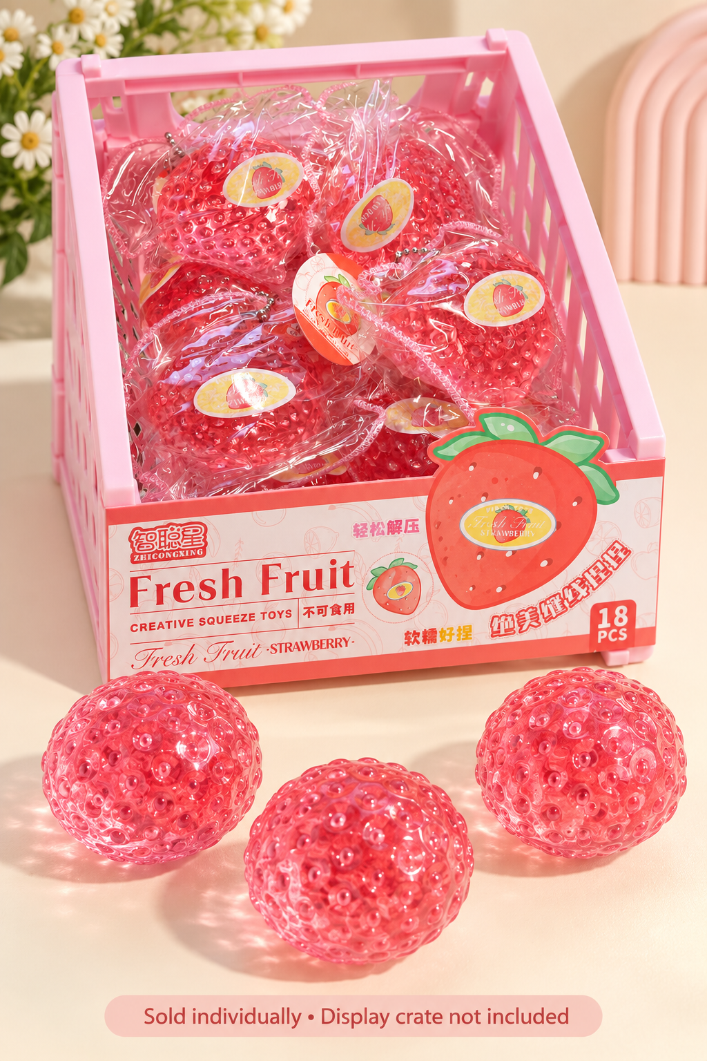 Pink display crate with packaged strawberry squishies and loose translucent pink toys; sold individually, crate excluded.