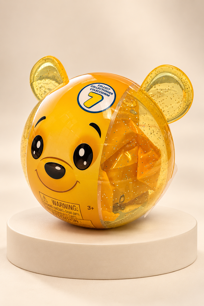 Sealed yellow glitter bear capsule, sharp right studio view on ivory pedestal