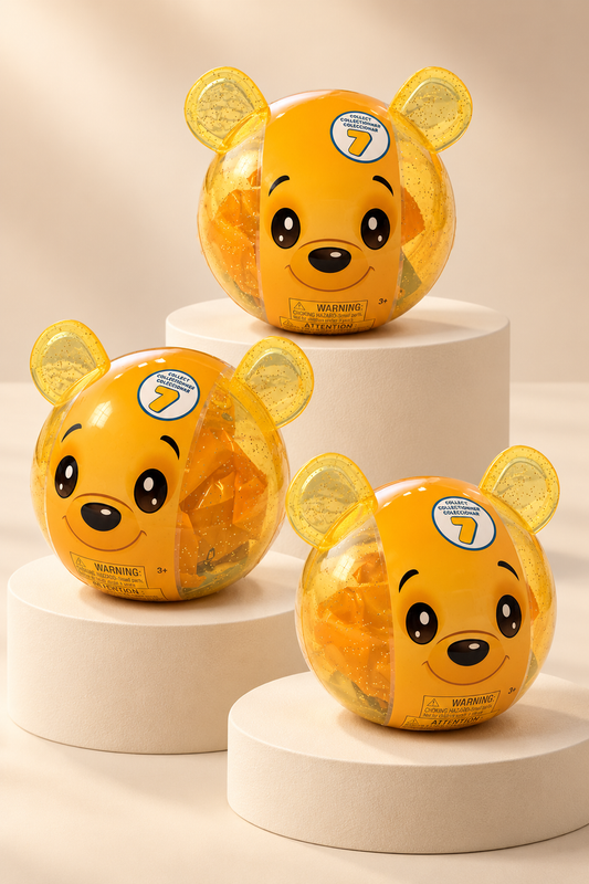 Yellow glitter bear capsule shown in three views on tiered ivory pedestals; one capsule product